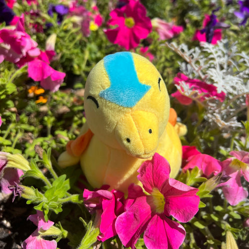 Yellow plush toy with a blue patch surrounded by pink flowers